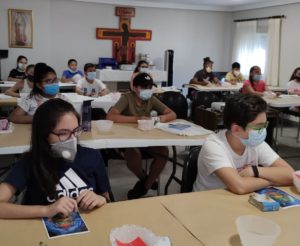Hay varios niños en la aula parroquial haciendo manualidades.