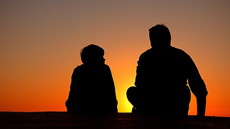 Dos personas en una puesta de sol hablando.